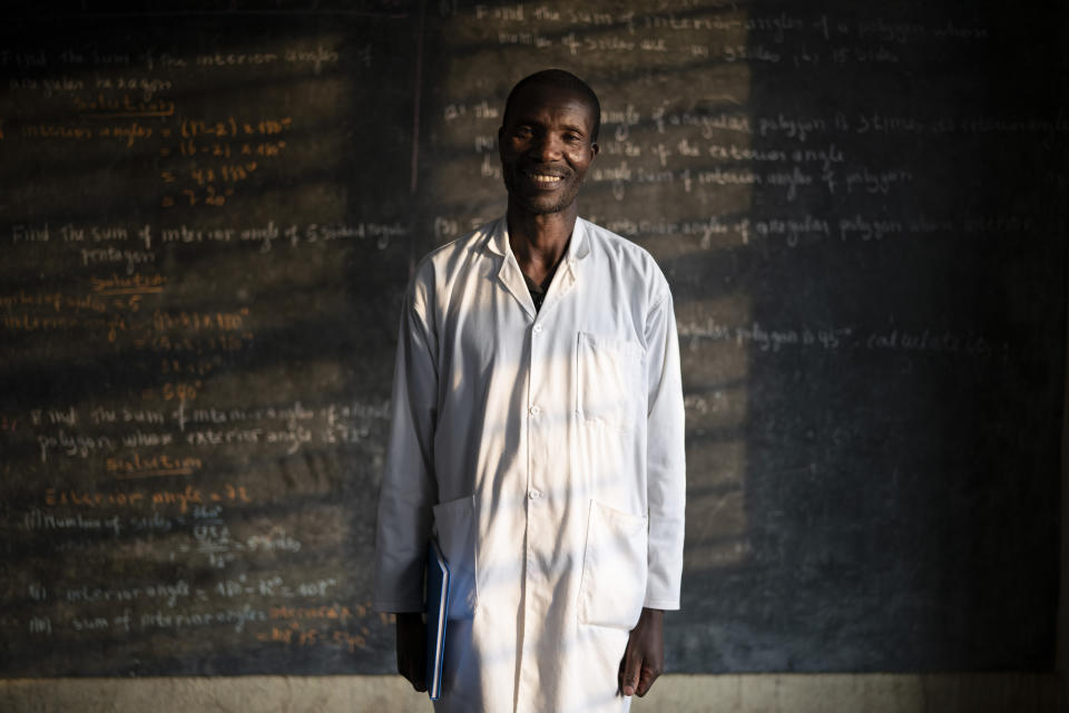 In this Sept. 5, 2019 photo, Fabien Uwimana, a French and English teacher, poses for a portrait at the Nyabitsinde Primary School in Kinigi, Rwanda. “The money that built this school comes from tourism,” he says. “More children today can go to school.” (AP Photo/Felipe Dana)