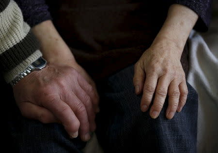 72-year-old Kanemasa Ito (L) holds hands with his 68-year-old wife Kimiko, who was diagnosed with dementia 11 years ago, on a sofa at their home in Kawasaki, south of Tokyo, Japan, April 6, 2016. REUTERS/Issei Kato