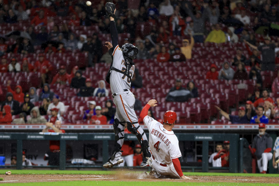 San Francisco Giants' Michael Papierski, left, leaps to field the ball as Cincinnati Reds' Matt Reynolds scores a run on a single by Tyler Stephenson during the third inning of a baseball game in Cincinnati, Friday, May 27, 2022. (AP Photo/Aaron Doster)
