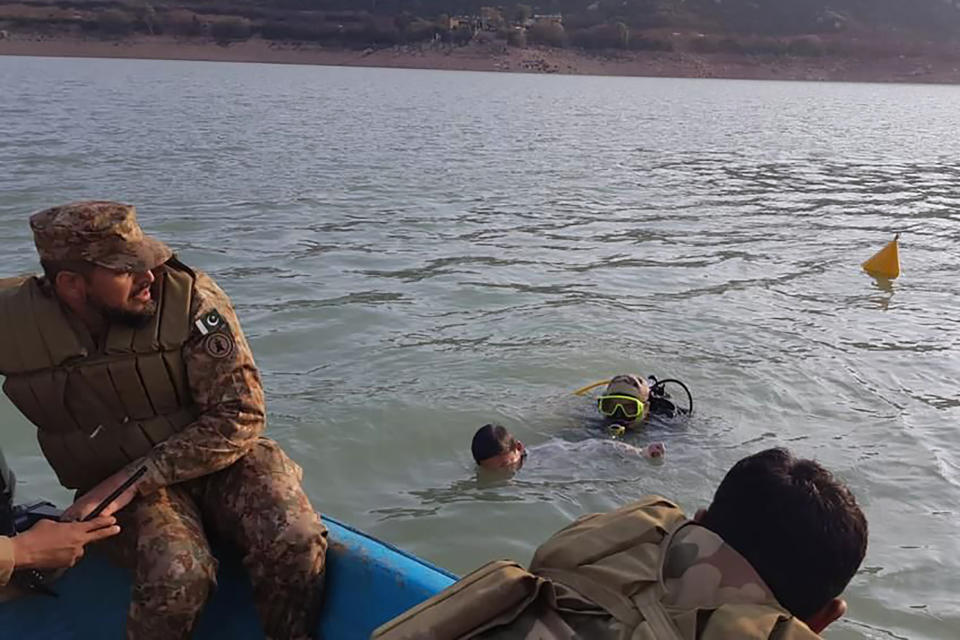 In this photo released by Inter Services Public Relations, an army diver recovers a child body during search operation in Tanda Dam, in Kohat, a district of Pakistan's Khyber Pakhtunkhwa province, Tuesday, Jan. 31, 2023. The vessel was carrying children and teachers from a seminary on a picnic. Police on Sunday said several students drowned after their boat capsized in Tanda Dam in Khyber Pakhtunkhwa province. (Inter Services Public Relations via AP)