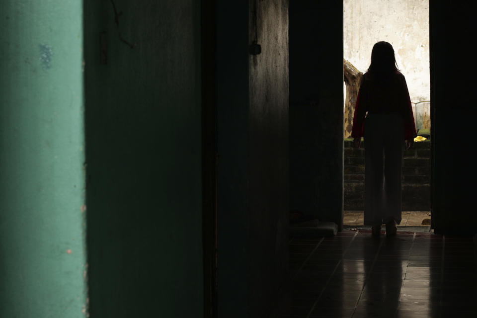 A Salvadoran businesswoman, who is one of the applicants of a small refugee program that was shut down by President Donald Trump, stands in a hallway of her home in Santa Ana, El Salvador, Saturday, Aug. 22, 2020. After a court settlement and a judge order, however, she and about 2,700 other Central Americans who had been conditionally approved, have been allowed to move forward in the process and travel to the U.S. The woman is now waiting to finally join her husband and daughter in the U.S. but the new coronavirus pandemic has delayed her arrival. (AP Photo/Salvador Melendez)