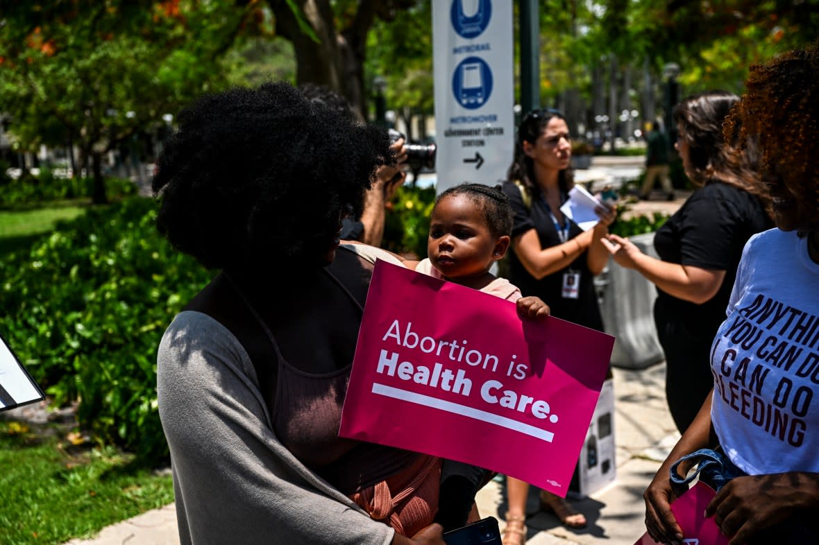 Tifanny Burks holds Novah Smith (2) as the members of Florida Planned Parenthood PAC Abortion rights activists hold placard during a protest after the 6-3 ruling in Dobbs v. Jackson Women's Health Organization which overturns the landmark abortion Roe v. Wade case, in Miami, Florida, on June 24, 2022. The US Supreme Court on Friday ended the right to abortion in a seismic ruling that shreds half a century of constitutional protections on one of the most divisive and bitterly fought issues in American political life. The conservative-dominated court overturned the landmark 1973 "Roe v Wade" decision that enshrined a woman's right to an abortion and said individual states can permit or restrict the procedure themselves. (Photo by CHANDAN KHANNA / AFP) (Photo by CHANDAN KHANNA/AFP via Getty Images)