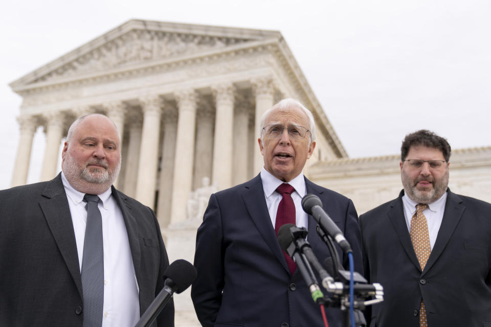 Attorney Eric Schnapper, center, accompanied by attorney Keith Altman, left, and attorney Robert Tolchin, right, speaks to members of the media, Wednesday, Feb. 22, 2023, in Washington, after the Supreme Court heard oral arguments. The Supreme Court is weighing Wednesday whether Facebook, Twitter and YouTube can be sued over a 2017 Islamic State group attack on a Turkish nightclub based on the argument the platforms assisted in fueling the growth of the terrorist organization. (AP Photo/Andrew Harnik)