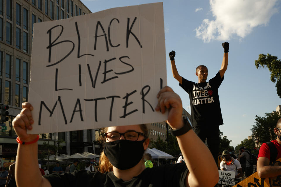 FILE - In this June 24, 2020, file photo, Antonio Mingo, right, holds his fists in the air as demonstrators protest in front of a police line on a section of 16th Street that's been renamed Black Lives Matter Plaza, in Washington. (AP Photo/Jacquelyn Martin, File)