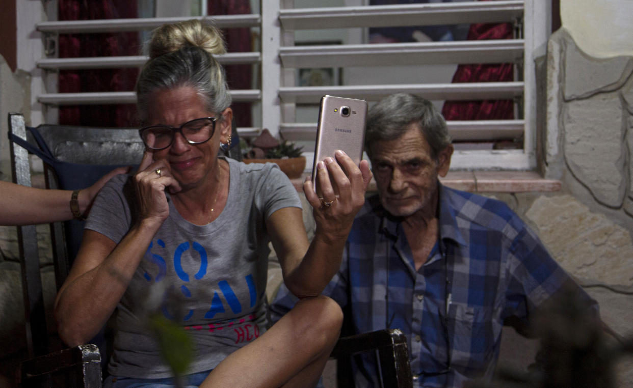Marialys Gonzalez Lopez and her father, Alejandro Gonzalez Lopez, hold a video call with her daughters Merlyn and Melanie, and Melanie's daughter, Madisson, from their home in Havana, Cuba, Tuesday, Jan. 3, 2023. (AP Photo/Ismael Francisco)