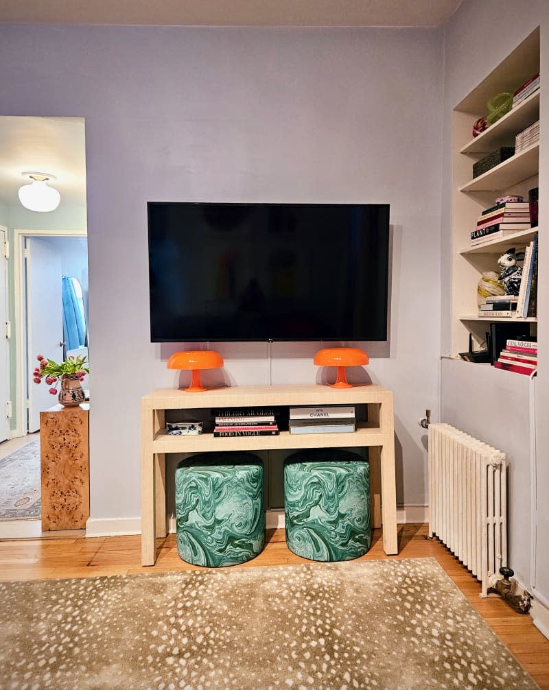 TV and small console table with 2 marbled green ottomans underneath