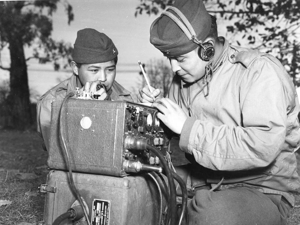 Private First Class Preston Toledo and Private First Class Frank Toledo, cousins and full-blood Navajo Indians, attached to a Marine Artillery Regiment in the South Pacific, relay orders over a field radio in their native tongue, Ballarat, July 7, 1943.