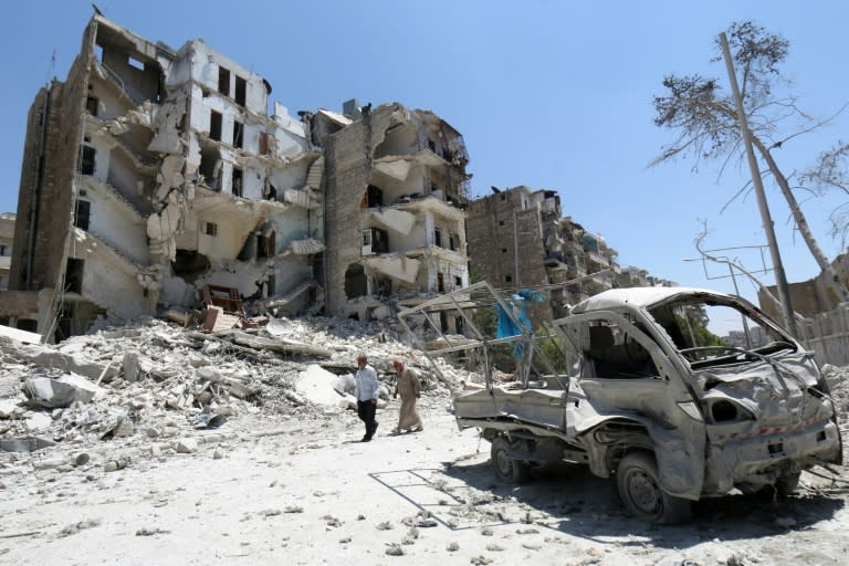 Syrian men walk amidst the rubble and debris in the Qadi Askar district of the northern city of Aleppo, July 5, 2015