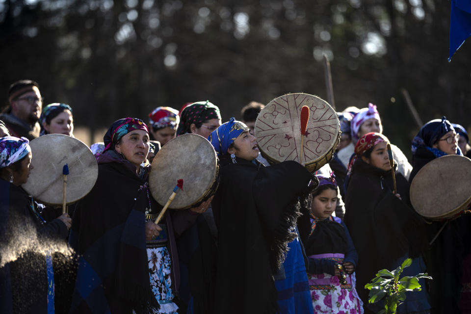 Millaray Huichalaf, center, a Mapuche machi, or healer and spiritual guide, beats on a ceremonial drum known as a kultrun, to accompany a game of palin, a traditional game similar to field hockey, in Carimallin, southern Chile, on Sunday, June 26, 2022. (AP Photo/Rodrigo Abd)