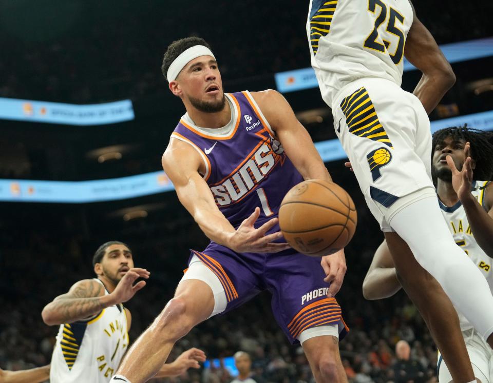 Phoenix Suns guard Devin Booker (1) passes the ball off against Indiana Pacers forward Jalen Smith (25) during the first quarter at Footprint Center in Phoenix on Jan. 21, 2024.