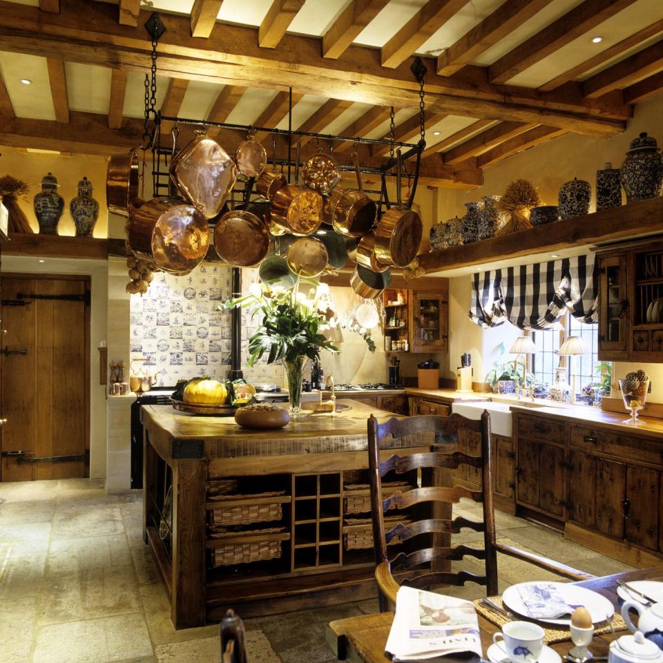 <p>Esta cocina es puramente rústica. Antigua, con muebles en madera oscura, utensilios en la parte superior de la isla, y vigas de madera por todas partes en el techo. Sin duda, una cocina de estilo rural muy auténtica.</p>