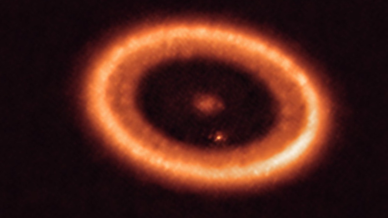  Blurry orange, concentric rings surround a central star in deep space. 