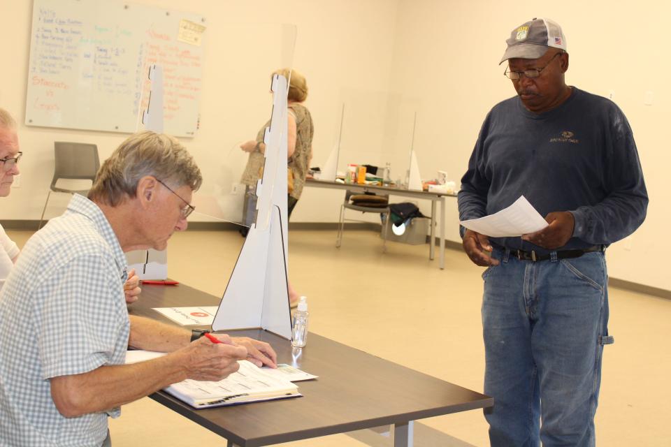 Anderson County Election Commission poll worker George Lobdell, sitting, helped Tom Moton sign in to vote at the Oak Ridge Senior Center on Aug. 4.