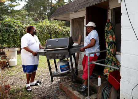 Minnie Williams (R) and her grandson James Williams remove a gas grill while preparing her home to reconnect the electricity after flooding due to Hurricane Florence receded in Fair Bluff, North Carolina, U.S. September 29, 2018. REUTERS/Randall Hill