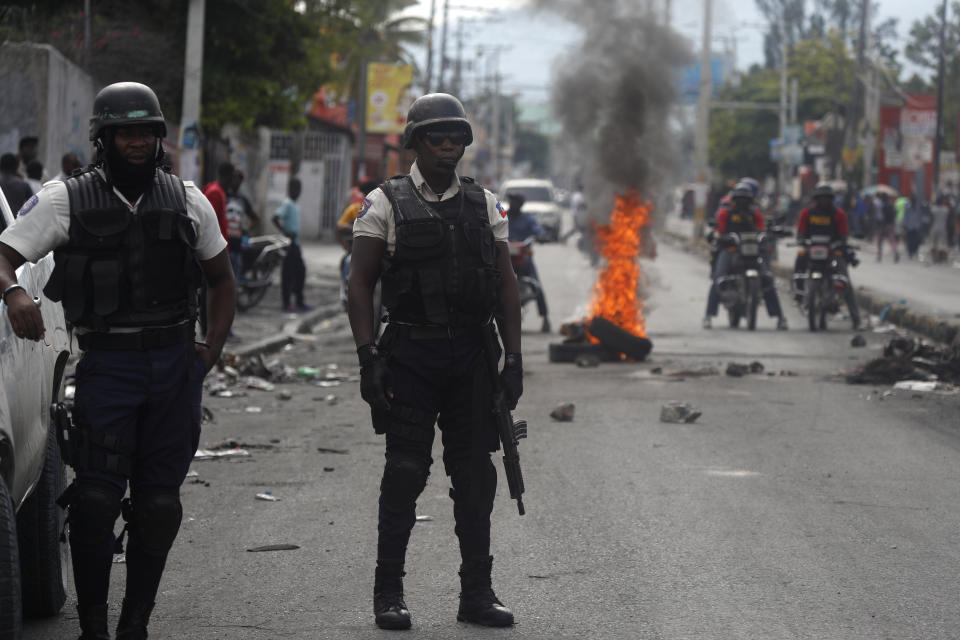 Police stand near a barricade built by protesters in Port-au-Prince, Haiti, Monday, Sept. 30, 2019. Opposition leaders are calling for a nationwide push Monday to block streets and paralyze Haiti's economy as they press for Moise to give up power, and tens of thousands of their young supporters were expected to heed the call. (AP Photo/Rebecca Blackwell)
