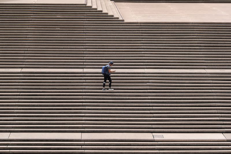 A lone man stands on the steps of the Sydney Opera House in Sydney