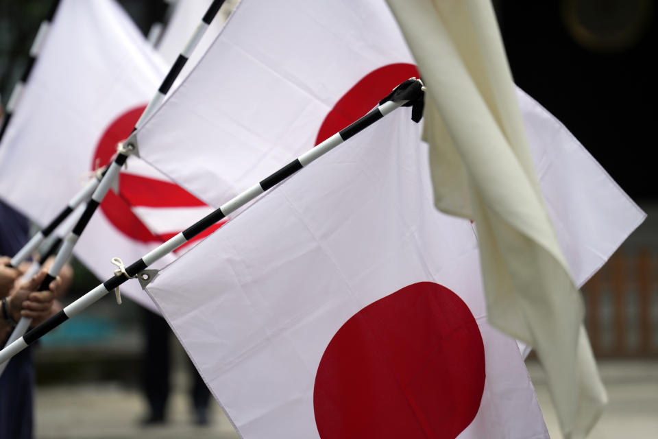 Members of right wing groups with Japanese national flags, stand at the Yasukuni Shrine, which honors Japan's war dead, Tuesday, Aug. 15, 2023, in Tokyo. Japan holds annual memorial service for the war dead as the country marks the 78th anniversary of its defeat in the World War II. (AP Photo/Eugene Hoshiko)
