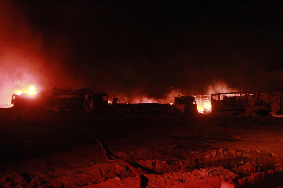 A fire of a burning oil tanker is seen where firefighters try to extinguish after an explosion at the Islam Qala border with Iran, in Herat Province, west of Kabul, Afghanistan, Saturday, Feb. 13, 2021. The fuel tanker exploded Saturday at the Islam Qala crossing in Afghanistan's western Herat province on the Iranian border, injuring multiple people and causing the massive fire that consumed more than 500 trucks carrying natural gas and fuel, according to Afghan officials and Iranian state media. (AP Photo/Hamed Sarfarazi)