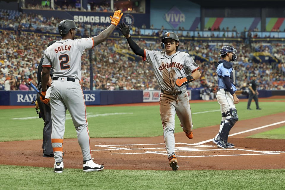 San Francisco Giants' Jung Hoo Lee, center, celebrates with Jorge Soler after scoring behind Tampa Bay Rays catcher Rene Pinto during the first inning of a baseball game Sunday, April 14, 2024, in St. Petersburg, Fla. (AP Photo/Mike Carlson)