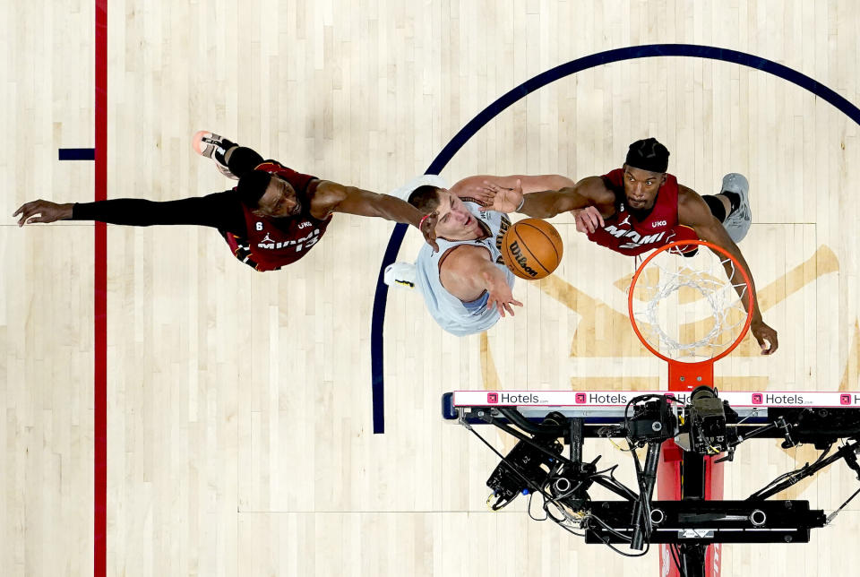 Denver Nuggets center Nikola Jokić reaches for the ball against Miami Heat center Bam Adebayo and forward Jimmy Butler during the second half in Game Five of the 2023 NBA Finals at Ball Arena in Denver, Colorado, on June 12, 2023.