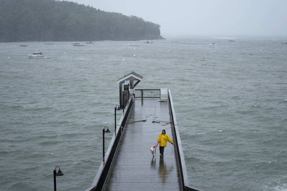 A girl braves wet and windy conditions to walk her dog on a pier during storm Lee, Saturday, Sept. 16, 2023, in Bar Harbor, Maine. Severe conditions were predicted across parts of Massachusetts and Maine, and hurricane conditions could hit the Canadian provinces of New Brunswick and Nova Scotia, where the storm, Lee, downgraded early Saturday from hurricane to post-tropical cyclone, was expected to make landfall later in the day. (AP Photo/Robert F. Bukaty)
