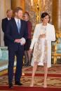 <p>The Duchess of Sussex paired a metallic brocade dress with a rose gold clutch, nude Paul Andrew heels, and a recycled <a href="https://www.amandawakeley.com/us/cream-sculpted-tailoring-coat" rel="nofollow noopener" target="_blank" data-ylk="slk:Amanda Wakely cream coat;elm:context_link;itc:0;sec:content-canvas" class="link ">Amanda Wakely cream coat</a>, for Prince Charles's 50th Anniversary Investiture reception at Buckingham Palace. </p>