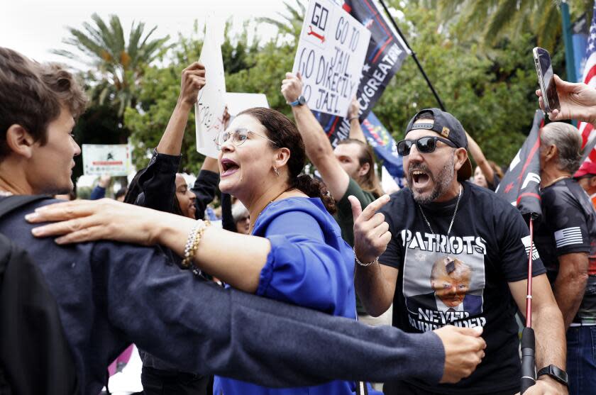 ANAHEIM-CA-SEPTEMBER 29, 2023: Ada Briceno, chair of the Democratic Party of Orange County, center, tries to keep their group from engaging with Trump supporters, right, during the California Republican Party Convention at the Anaheim Marriott Hotel on Friday, September 29, 2023. (Christina House / Los Angeles Times)