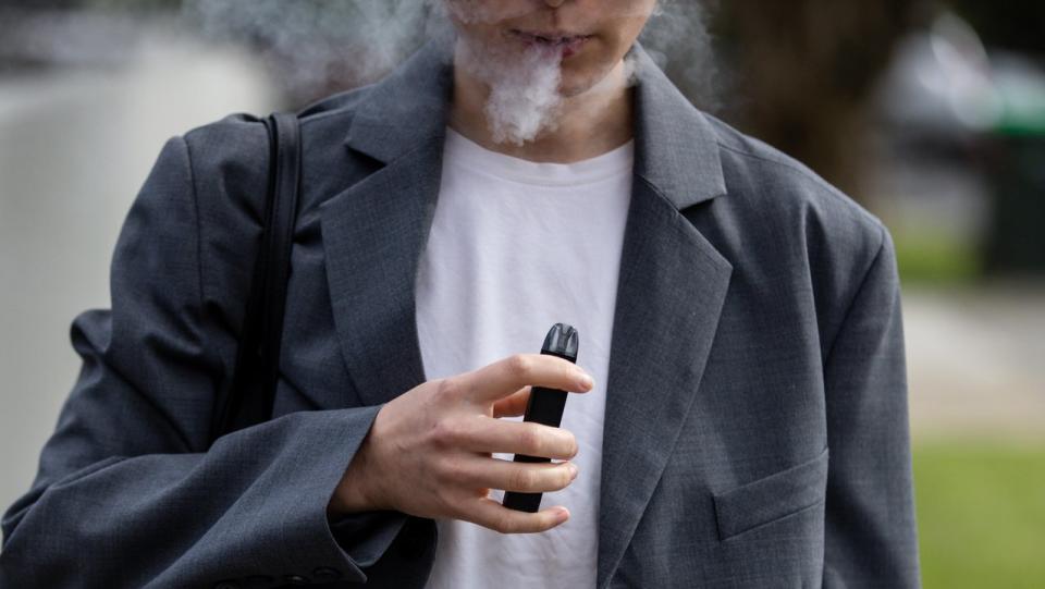 A woman smokes a vape.