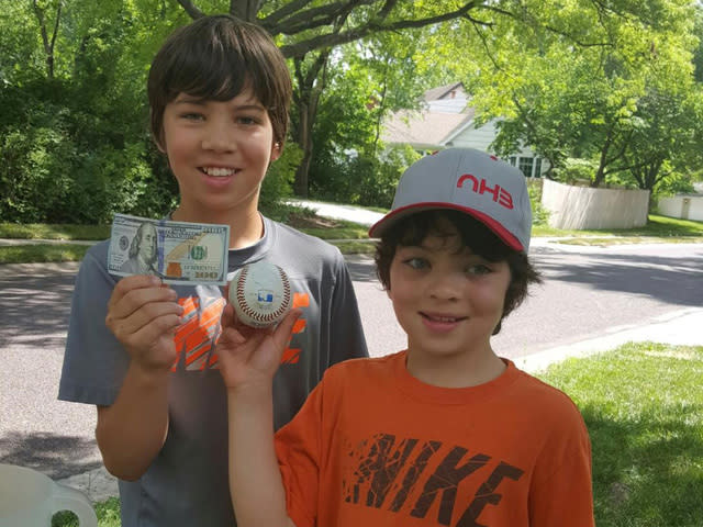 Raheem and Solomon Hirsch pose with the ball and $100 bill that Yordano Ventura gave them. (KSHB)