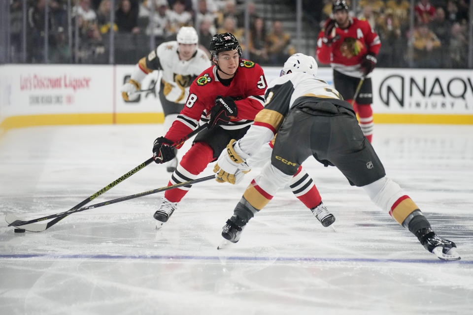 Chicago Blackhawks center Connor Bedard (98) knocks the puck past Vegas Golden Knights defenseman Brayden McNabb (3) during the first period of an NHL hockey game Friday, Oct. 27, 2023, in Las Vegas. (AP Photo/John Locher)