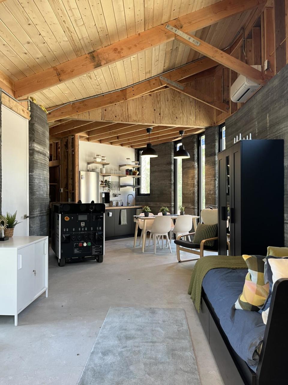 A view of a studio apartment space features a sleeping area in the foreground and gently curving kitchen at the rear.