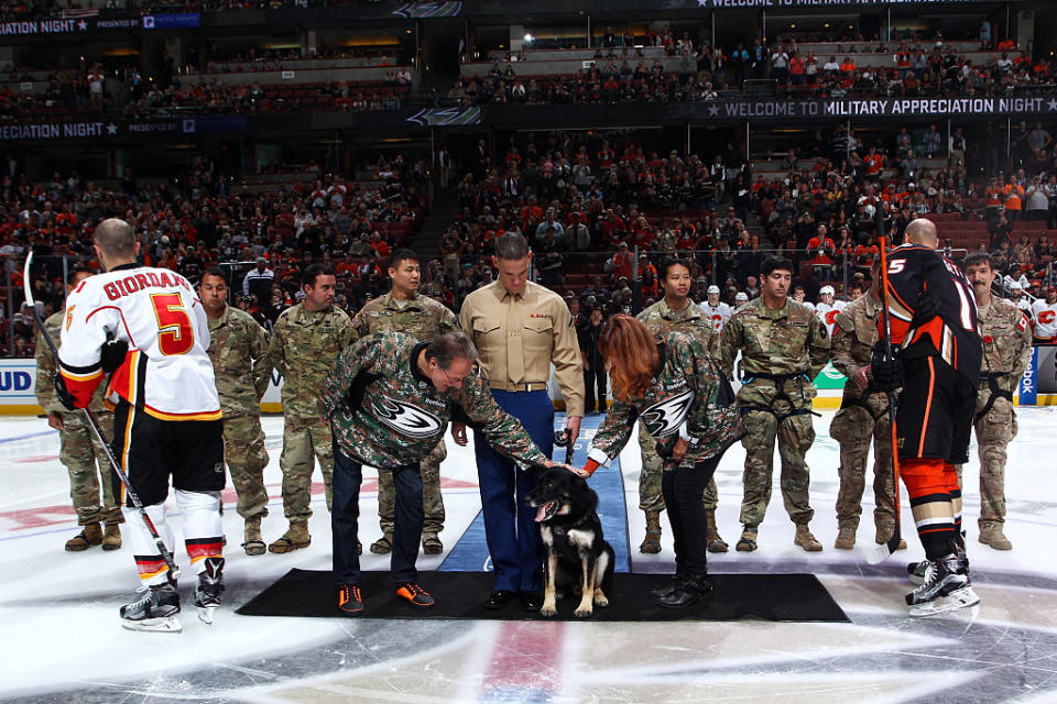 ANAHEIM, CA - NOVEMBER 6: Corporal Nero and Lance Corporal Brandon C. Benningfield, center, are joined by Ryan Kesler #17 of the Anaheim Ducks, Mark Giordano #5 of the Calgary Flames, Ducks owners Henry Samueli, left, and Susan Samueli, and members of the Canadian Special Operations Forces Command, U.S Special Forces Soldiers from Special Operations Detachment North, and the 128th Quartermaster Rigger Support Team for the ceremonial puck drop prior to the game between the Anaheim Ducks and the Calgary Flames on November 6, 2016 at Honda Center in Anaheim, California. (Photo by Debora Robinson/NHLI via Getty Images)