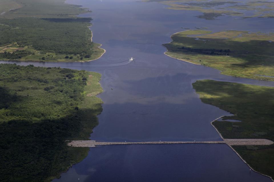 FILE - In this aerial Aug. 10, 2015 file photo made during a flight provided by the National Wildlife Federation and Southern Wings, a shrimp boat travels behind a rock dam built by the U.S. Army Corps of Engineers in the Mississippi River Gulf Outlet, in St. Bernard Parish, La. Floodwaters carried down from the Midwest are killing oysters and driving crabs, shrimp and finfish out of Louisiana and Mississippi bays and marshes to saltier waters. (AP Photo/Gerald Herbert, File)