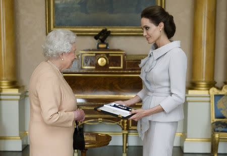 Actress Angelina Jolie is presented with the Insignia of an Honorary Dame Grand Cross of the Most Distinguished Order of St Michael and St George, by Britain's Queen Elizabeth in the 1844 room at Buckingham Palace in London October 10, 2014. REUTERS/Anthony Devlin/pool