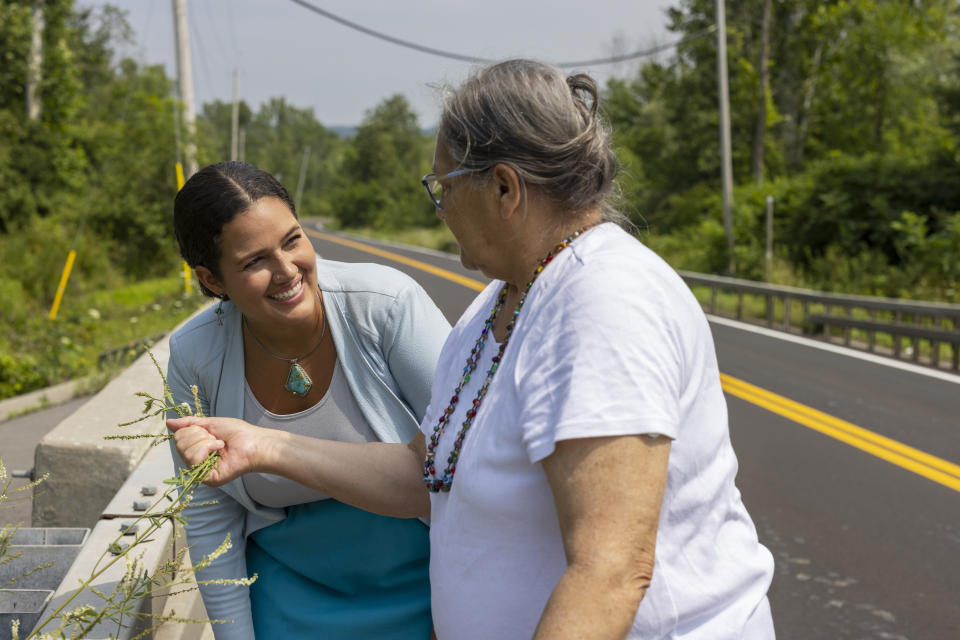 Jeanne Shanendoah holds out a plant to smell for Elizabeth Rule, deputy secretary for First Nations, Thursday, Aug. 3, 2023, on the Onondaga Nation territory in central New York. Rule's position was recently created by New York Gov. Kathy Hochul's administration. (AP Photo/Lauren Petracca)