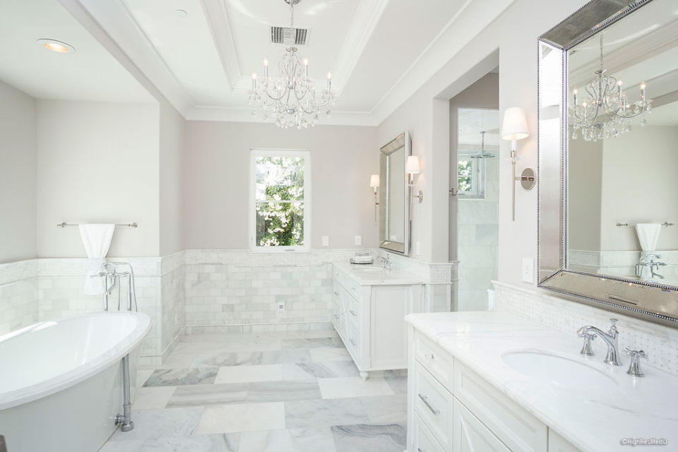 One bathroom features his-and-hers sinks, a chandelier, marble flooring, shower, and a tub.