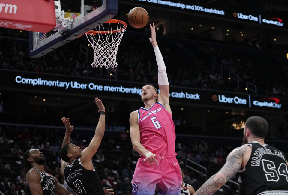 Washington Wizards center Kristaps Porzingis (6) goes up to shoot over San Antonio Spurs forward Keita Bates-Diop (31), forward Keldon Johnson (3), and forward Sandro Mamukelashvili (54) during the first half of an NBA basketball game Friday, March 24, 2023, in Washington. (AP Photo/Carolyn Kaster)