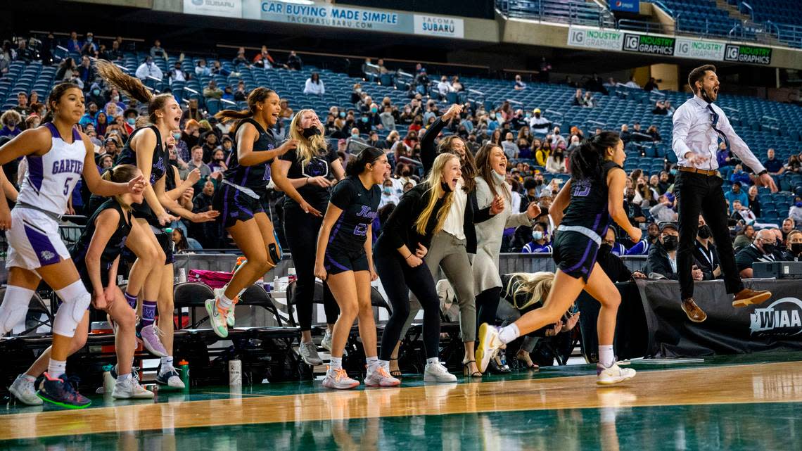 Lake Washington head coach Jeff Wilson (right) catches some air as his bench celebrates after forward Jolie Sim (15) scored a 3-pointer to give the Kangaroos a lead late in the fourth quarter of the Class 3A championship game against Garfield on Saturday, March 5, 2022, at the Tacoma Dome, in Tacoma, Wash.