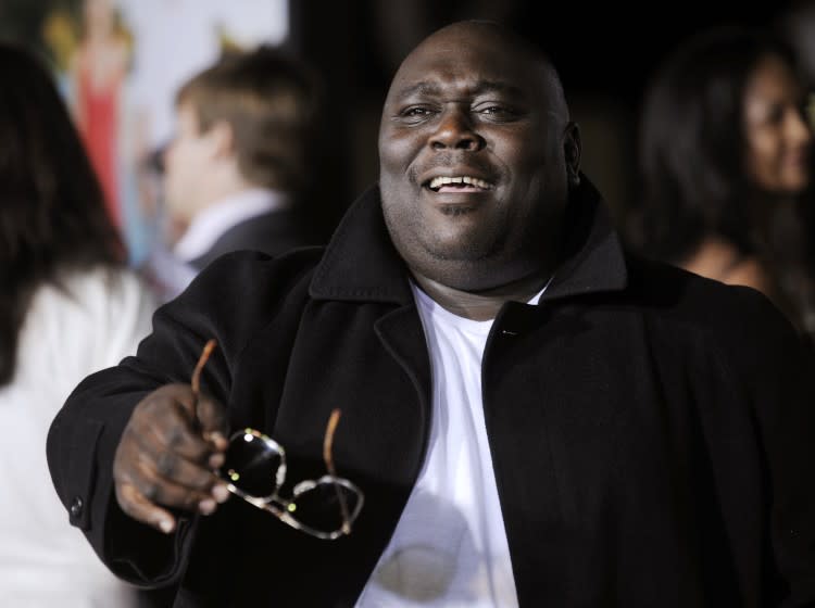 Faizon Love holding a pair of sunglasses