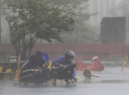 A man assisted a motorcyclist after he fell along a main road after strong winds brought by Typhoon Rammasun, locally called Glenda, battered the capital, metro Manila July 16, 2014. REUTERS/Romeo Ranoco