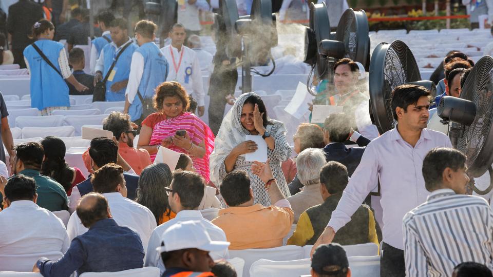 People stand near fans, on the day of India's Prime Minister Narendra Modi's swearing-in ceremony at the presidential palace in New Delhi, India, June 9, 2024