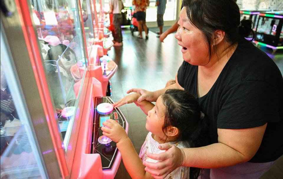 Chia Vue, right, of Fresno plays a claw machine game with her niece Mavis Vue, 4, at the Claw Daddy arcade at Fashion Fair in Fresno on Tuesday, Aug. 22, 2023.