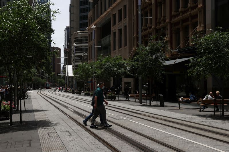 A person in a protective face mask crosses a street in Sydney