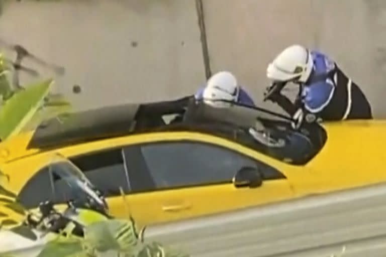 En esta imagen tomada de vídeo, dos agentes de policía interrogan a un conductor durante un control de tráfico mientras uno de los agentes apunta con un arma hacia la ventanilla del coche en Nanterre, Francia, el martes 27 de junio de 2023.