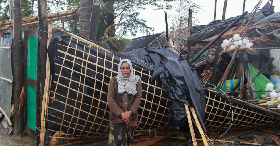 Una mujer se encuentra junto a su casa dañada después de que el ciclón Mocha tocara tierra en Shahpori Dwip, área de Teknuf cerca de Cox's Bazar, Bangladesh, 14 de mayo de 2023.