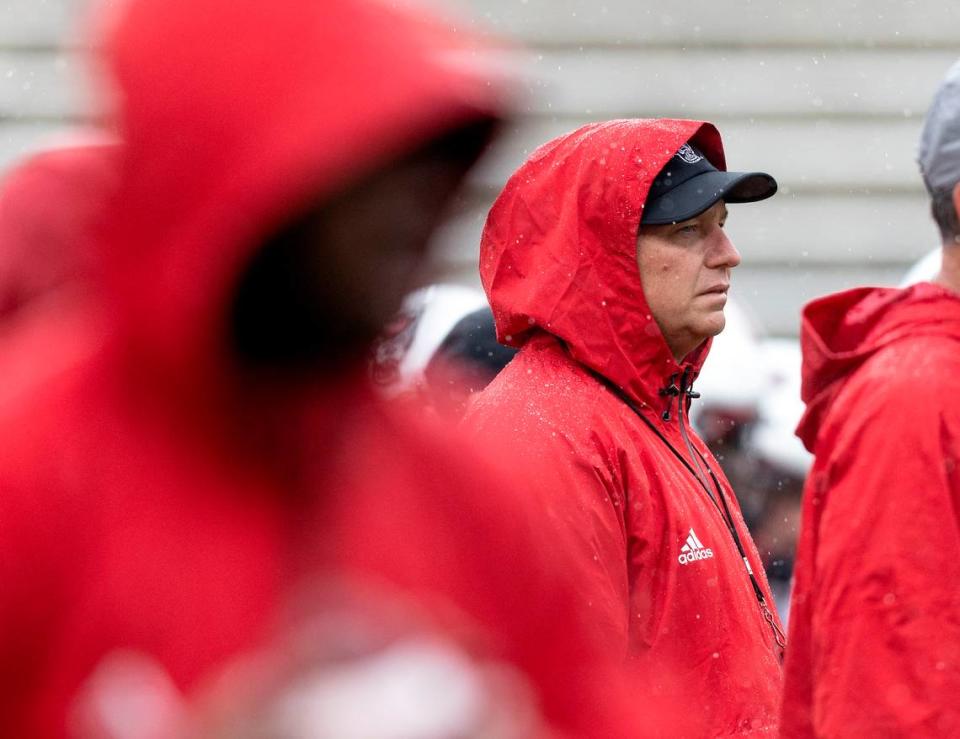 A steady rain falls as N.C. State head football coach Dave Doeren watches players warm up prior to the Wolfpack’s spring game at Carter-Finley Stadium on Saturday, April 8, 2023, in Raleigh, N.C.