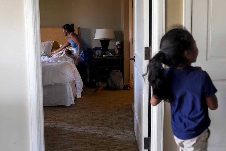 FILE - Zaevah Erickson-Castaneto, 7, jumps around as mother Erika Erickson checks on Mahina, 2, at the Honua Kai Resort & Spa, where they currently live after being displaced by the August wildfire Friday, Dec. 8, 2023, in the Kaanapali area of Lahaina, Hawaii. Erickson-Castaneto's great-grandmother Louise Abihai was among the victims in the deadliest U.S. wildfire in more than a century that took the lives of at least 100 people and destroyed most of the historic town of Lahaina. (AP Photo/Lindsey Wasson, File)