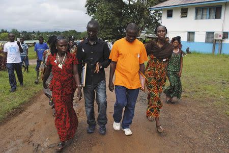 Four survivors of the Ebola outbreak, who were treated by Gorbee Logan, a Liberian doctor who says he has successfully treated Ebola patients with anti-retroviral drugs, walk at a clinic outside Monrovia October 3, 2014. REUTERS/James Giahyue