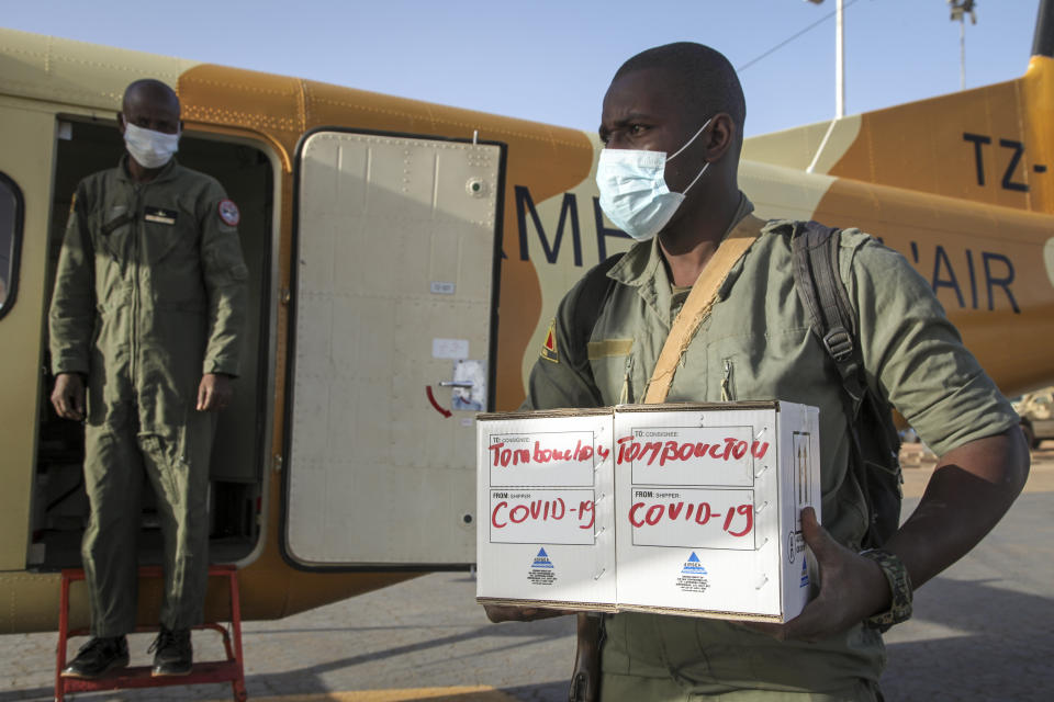 In this photo taken Friday, May 22, 2020, a Malian soldier in the capital Bamako, in Timbuktu, Mali, carries samples from patients in Timbuktu to a military plane flying them to be tested for the coronavirus. COVID-19 has made its way to Timbuktu, a town whose name has long been synonymous around the world with remoteness. (AP Photo/Baba Ahmed)