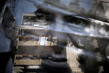 FILE PHOTO: Israeli national flags can be seen through a banner with the photo of Israeli PM Netanyahu during a LGBT community members protest in Tel Aviv